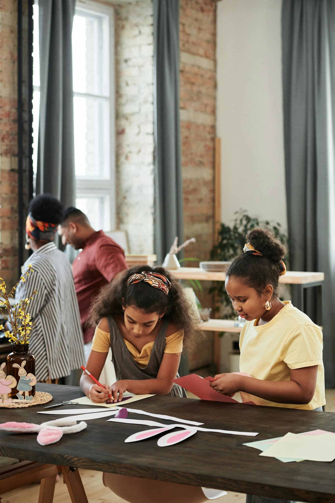 Two young girls enjoying a crafting session with their family indoors.
