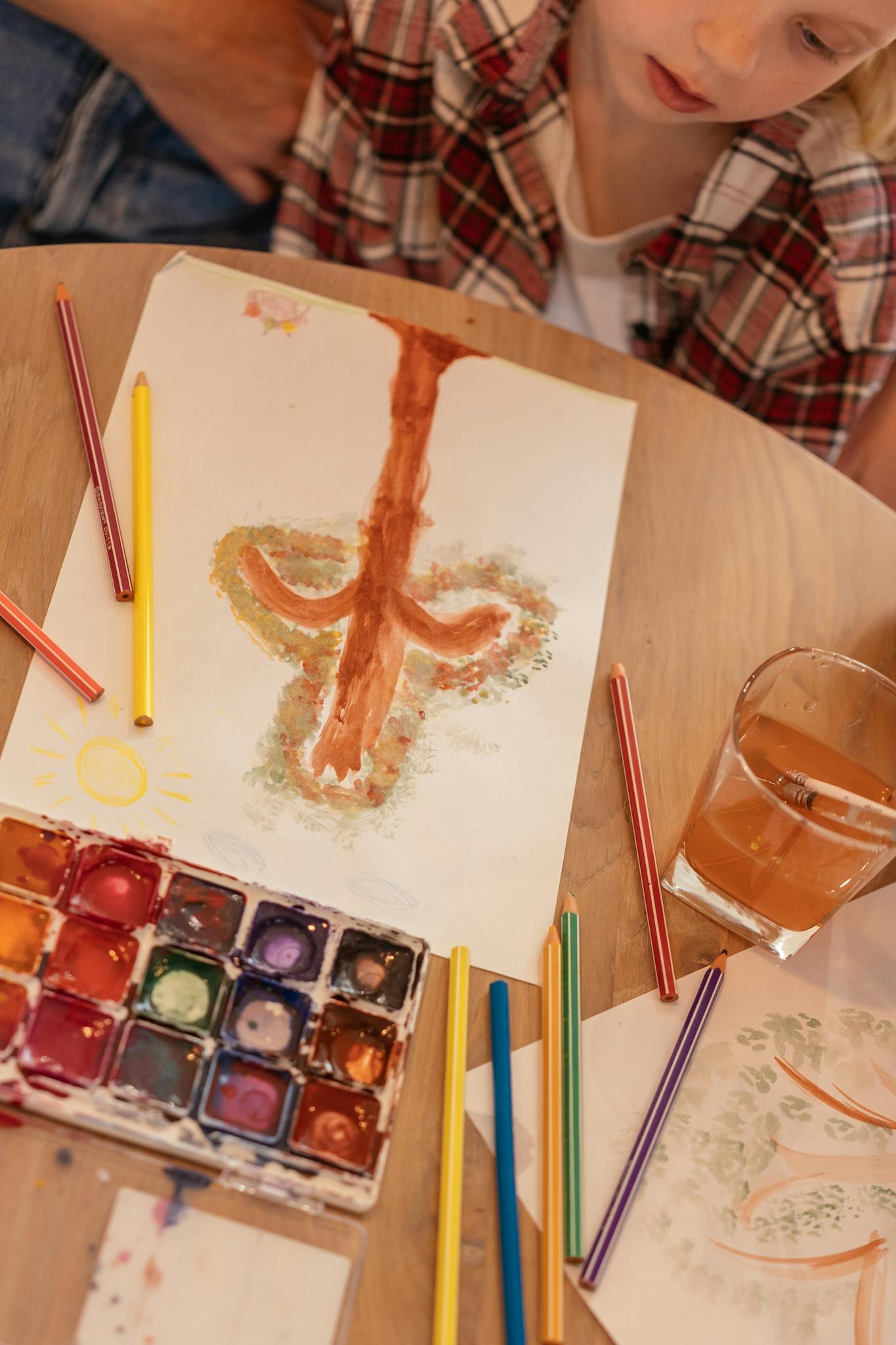 Young girl painting with watercolors and pencils in a vibrant artistic setting.